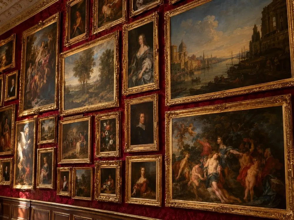 Ein Galerieflügel im Salonstil, bei dem die Gemälde rahmenlos vom Sockel bis zum Gesims gestapelt sind, mit kaum Beschriftungen daneben.